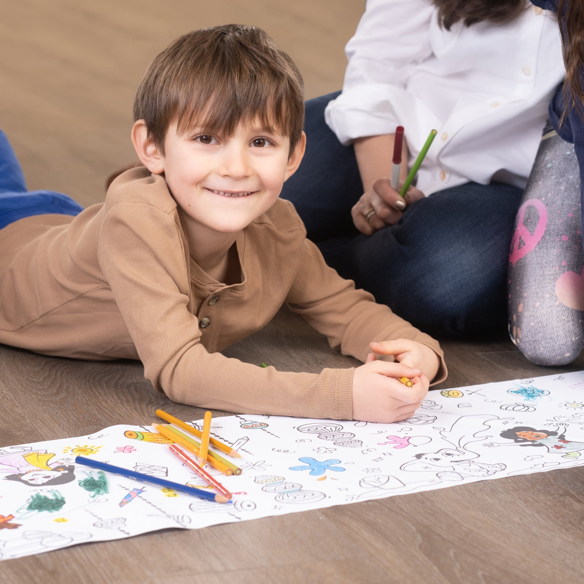 Children coloring on the festivals of India coloring roll sheet of paper with crayons on a wooden floor.